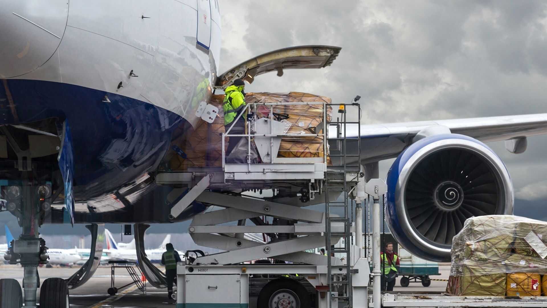 Operario de tierra en una plataforma elevadora cargando mercancía pesada en un avión de carga fletado.